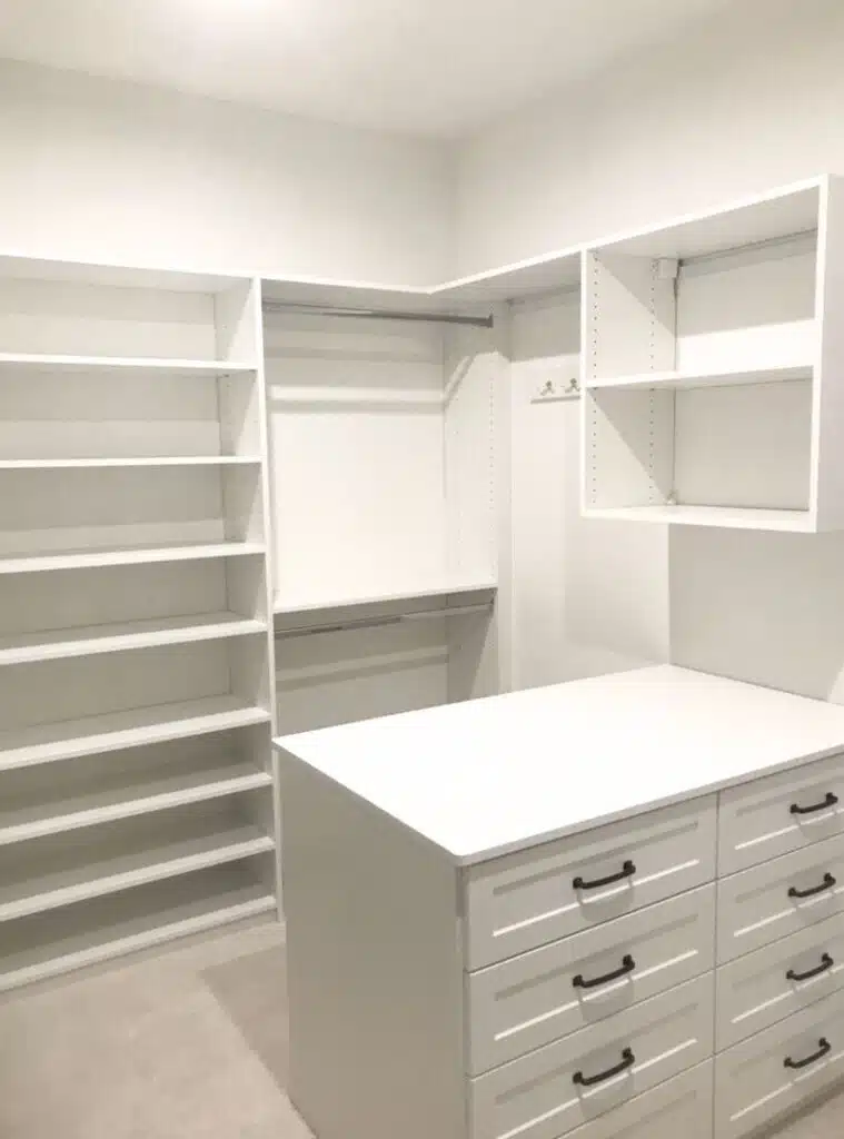 White walk-in closet with shoe shelving and drawer island