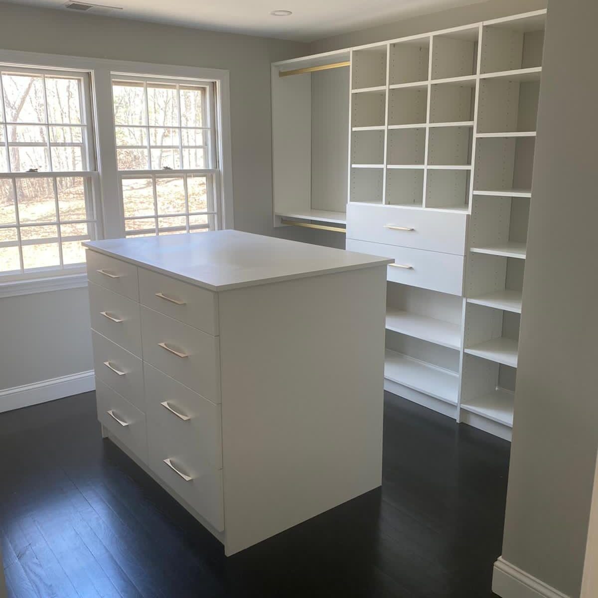 Custom white walk-in closet with drawer island and adjustable shelving installed by Singh Closets in Central Jersey